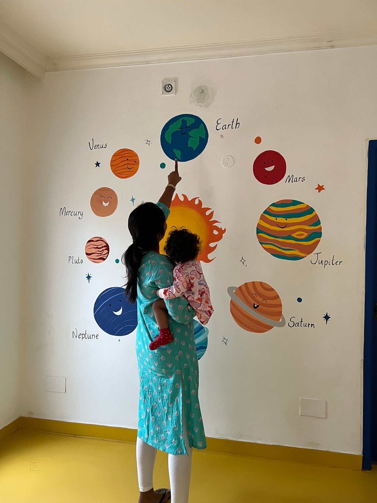 Teacher showing solar system wall mural to a child