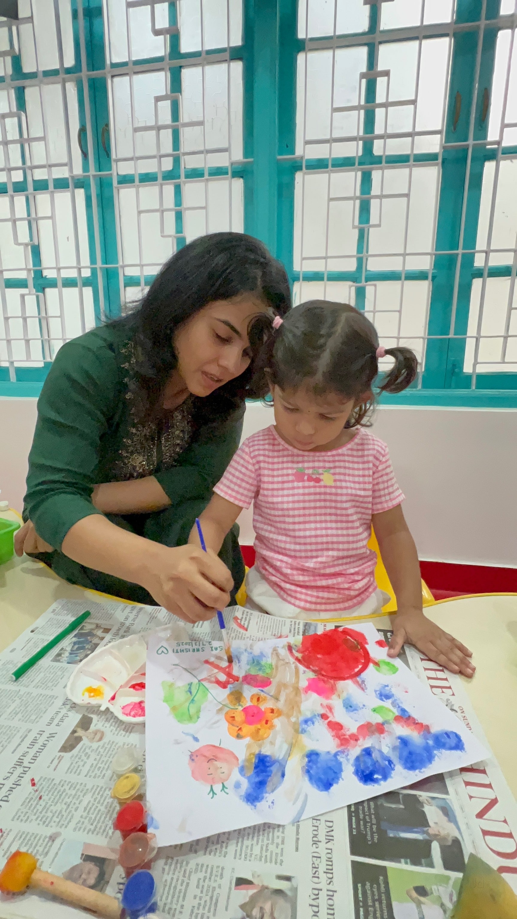 Teacher guiding a child through watercolor painting